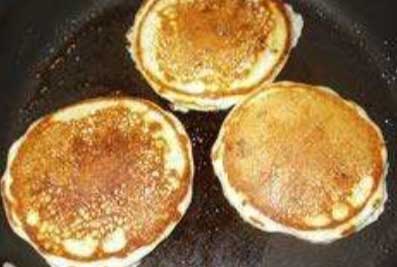 Three American pancakes sat in a frying pan