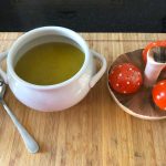 White Soup bowl of Ninja courgette and sweet potato soup in with condiments and a soup spoon on a wooden chopping board