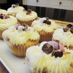 Vanilla cupcakes iced with buttercream frosting and topped with chocolate eggs on a white plate