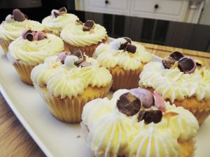 Vanilla cupcakes iced with buttercream frosting and topped with chocolate eggs on a white plate