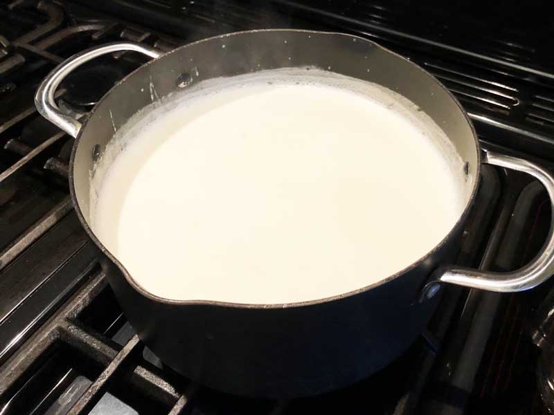 A pan of milk, rice, sugar and vanilla, the ingredients to make stove top rice pudding