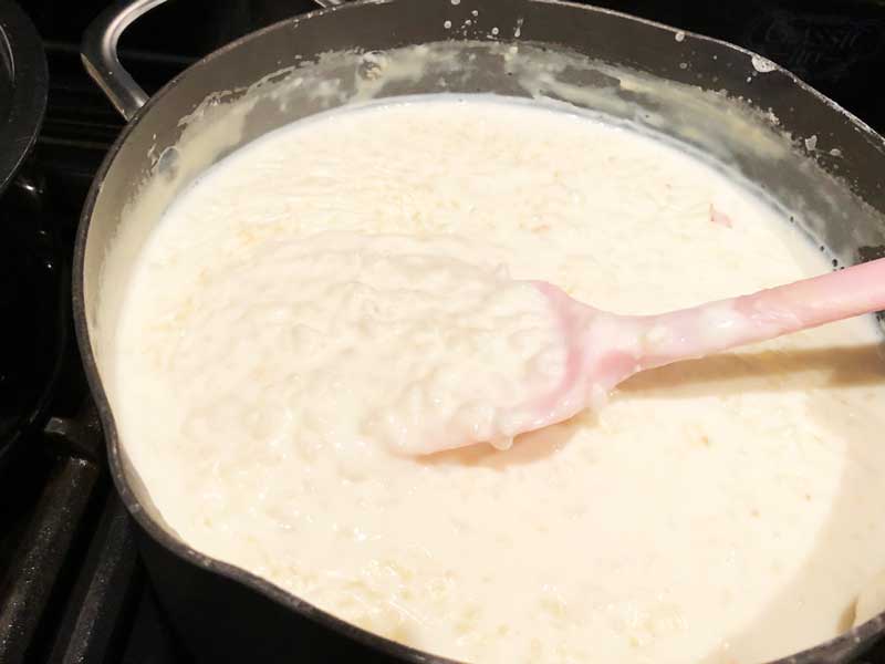 A pan of stove top rice pudding with a pink silicon spoon